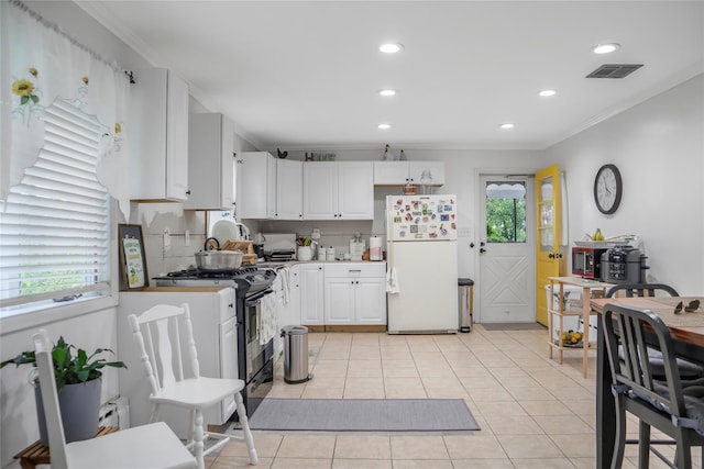 kitchen featuring light tile patterned floors, ornamental molding, visible vents, freestanding refrigerator, and black range with gas stovetop