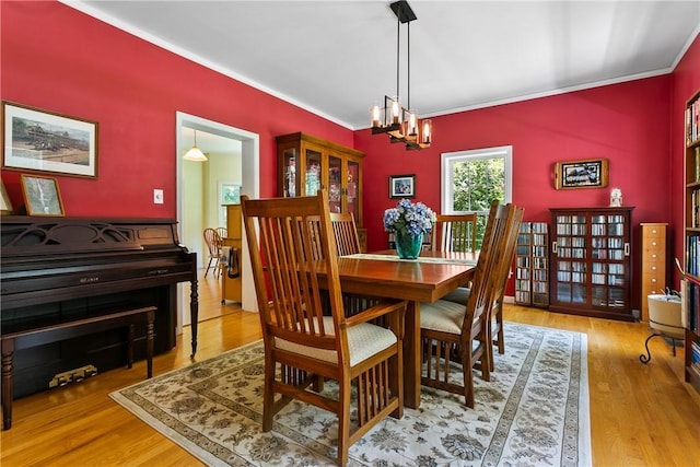 dining space with wood finished floors, a chandelier, and crown molding