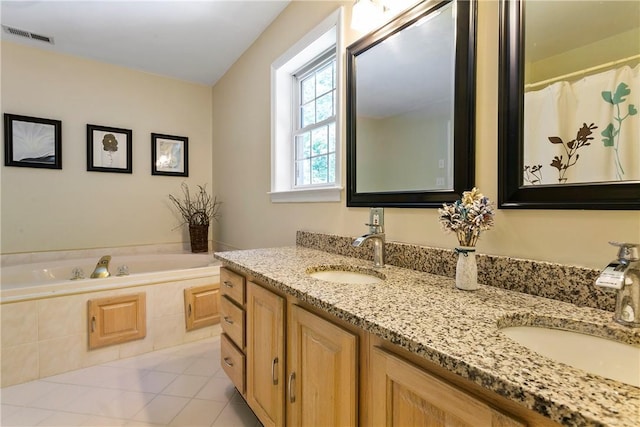 bathroom featuring a bath, double vanity, visible vents, and a sink