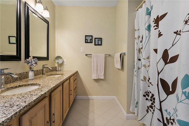 full bathroom with baseboards, double vanity, a sink, and tile patterned floors