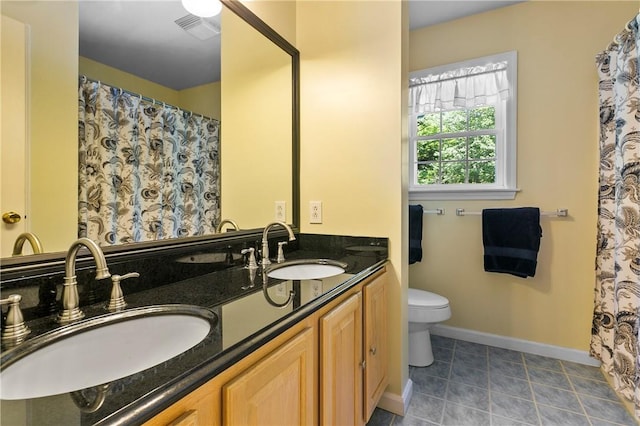 bathroom with toilet, a sink, double vanity, and visible vents