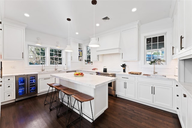 kitchen with stainless steel electric range oven, tasteful backsplash, a sink, white cabinets, and beverage cooler