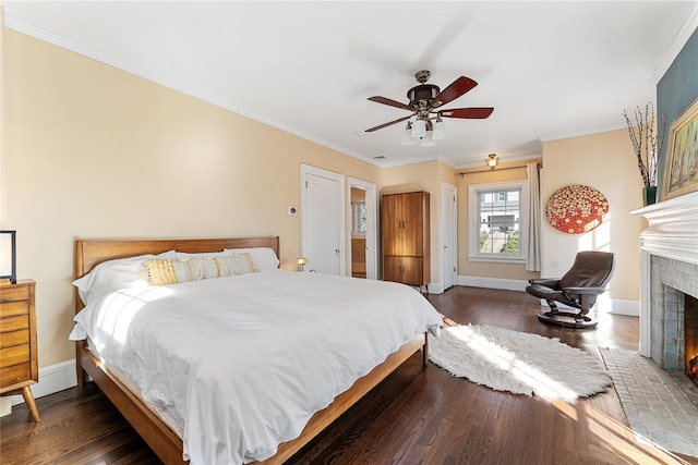 bedroom with crown molding, a brick fireplace, baseboards, dark wood-style floors, and a ceiling fan