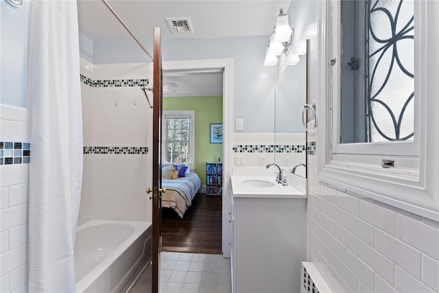 ensuite bathroom featuring vanity, tile patterned floors, tile walls, ensuite bathroom, and visible vents