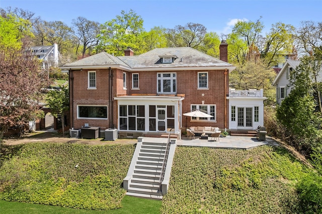 back of property featuring an outdoor living space, a chimney, a sunroom, a patio, and entry steps