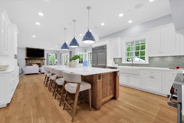 5 Briarcliff Rd, Chappaqua, NY 10514 - kitchen featuring stainless steel built in refrigerator, open floor plan, white cabinetry, a stone fireplace, and tasteful backsplash