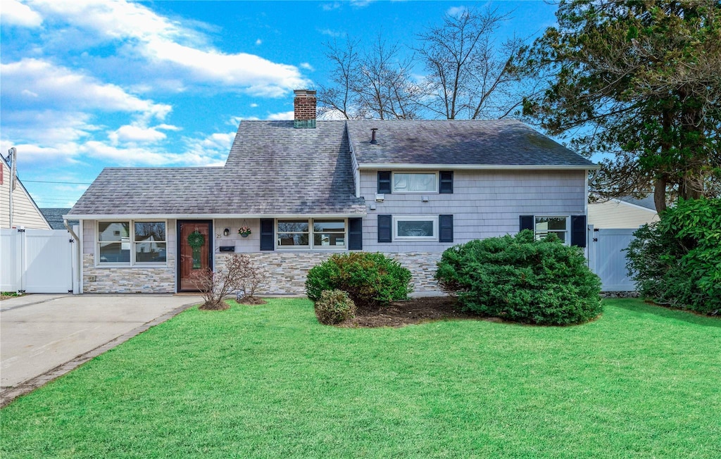 25 Lotus Ln, Westbury, NY 11590 - view of front of house with a chimney, a front yard, stone siding, and a gate