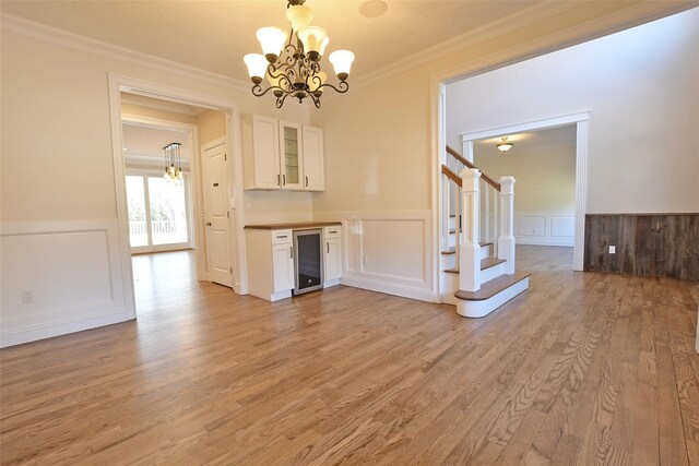 103 Silver Beech Ln, Calverton, NY 11933 - interior space featuring ornamental molding, wine cooler, light wood-type flooring, an inviting chandelier, and wainscoting