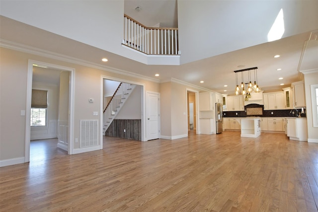 103 Silver Beech Ln, Calverton, NY 11933 - unfurnished living room with stairs, ornamental molding, visible vents, and light wood-style floors