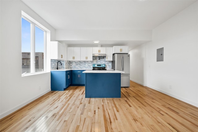kitchen featuring stainless steel appliances, light countertops, a sink, light wood-style flooring, and blue cabinetry