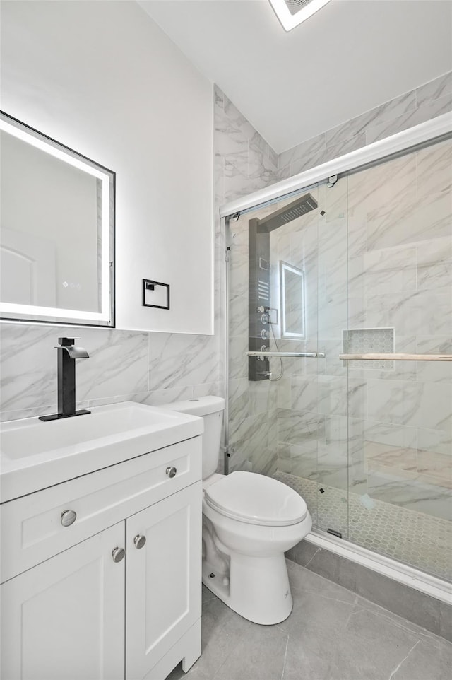 full bath featuring tile walls, toilet, vanity, and a stall shower