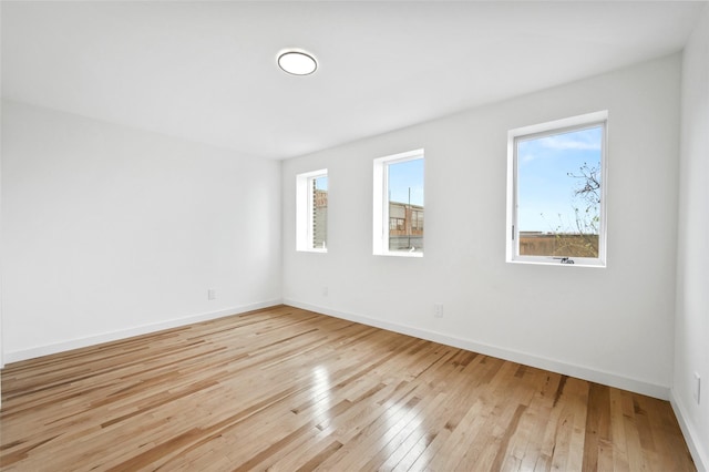 unfurnished room with baseboards and light wood-style flooring