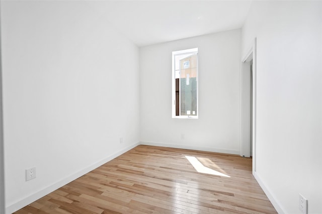 spare room with baseboards and light wood-style flooring