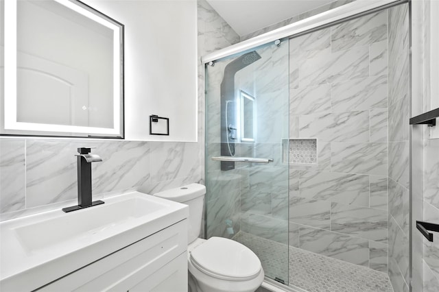 full bathroom featuring a stall shower, tile walls, vanity, and toilet