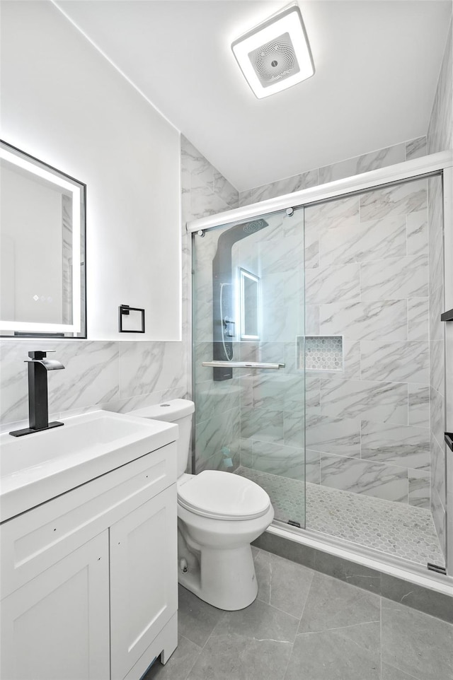 bathroom with a shower stall, vanity, tile walls, toilet, and visible vents