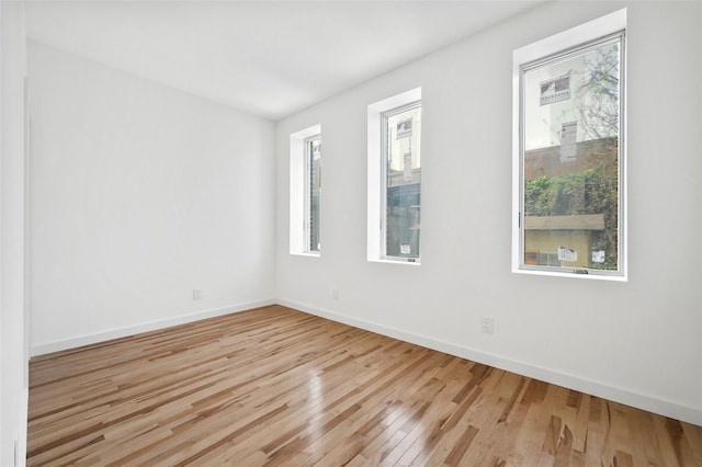 spare room with hardwood / wood-style floors and baseboards