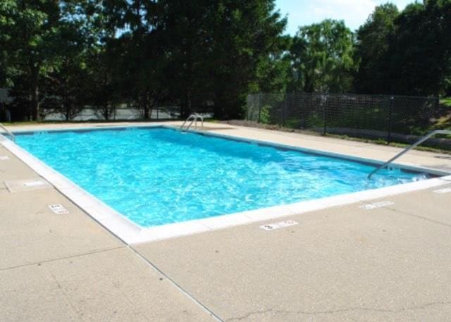 pool with a patio and fence