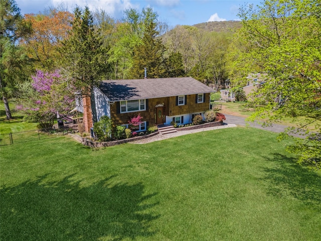 rear view of house featuring a lawn, fence, and a shingled roof