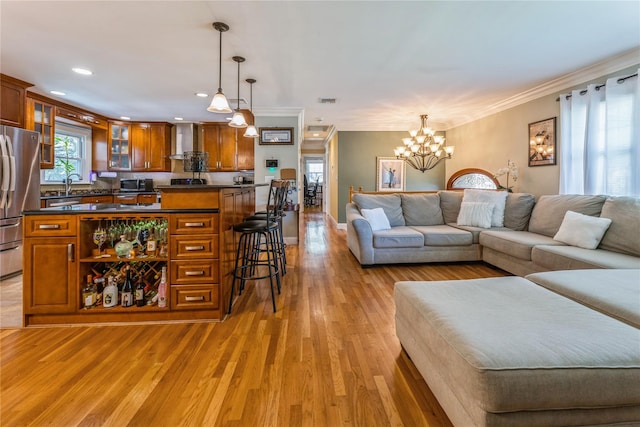living area with crown molding, recessed lighting, light wood finished floors, and a chandelier