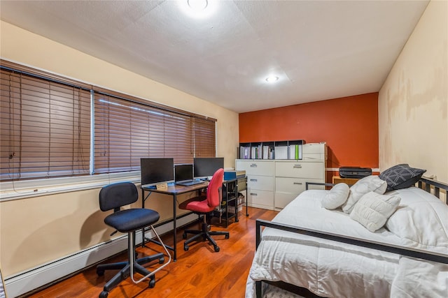 bedroom featuring wood finished floors and baseboard heating