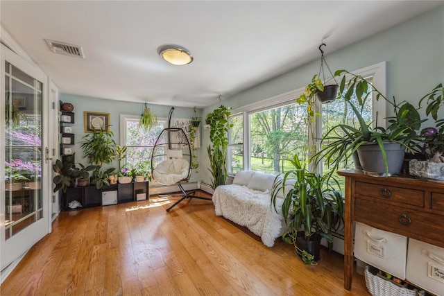 living area with a baseboard heating unit, visible vents, plenty of natural light, and light wood finished floors
