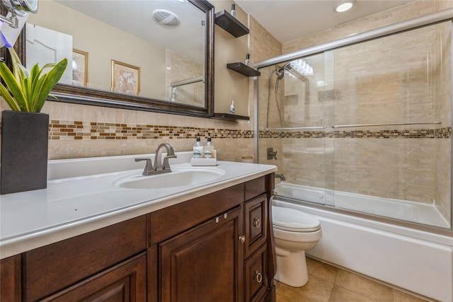 bathroom featuring tile walls, tile patterned flooring, vanity, bath / shower combo with glass door, and toilet