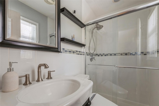 bathroom with a sink, tile walls, tasteful backsplash, and a stall shower