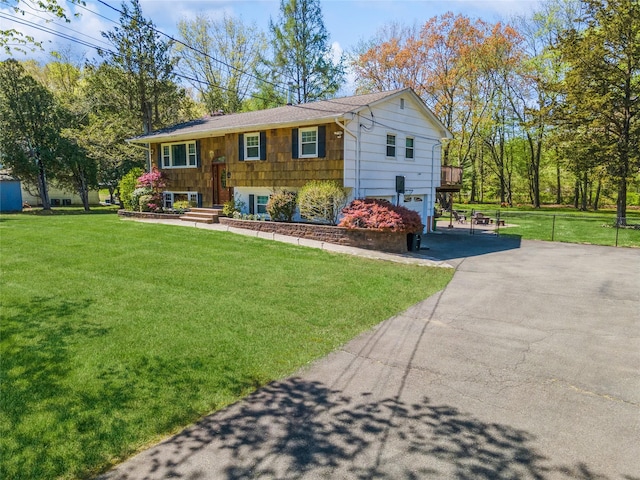 bi-level home featuring a garage, a front lawn, and aphalt driveway