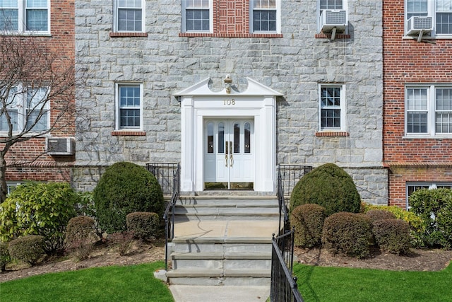 view of exterior entry featuring cooling unit, stone siding, and french doors