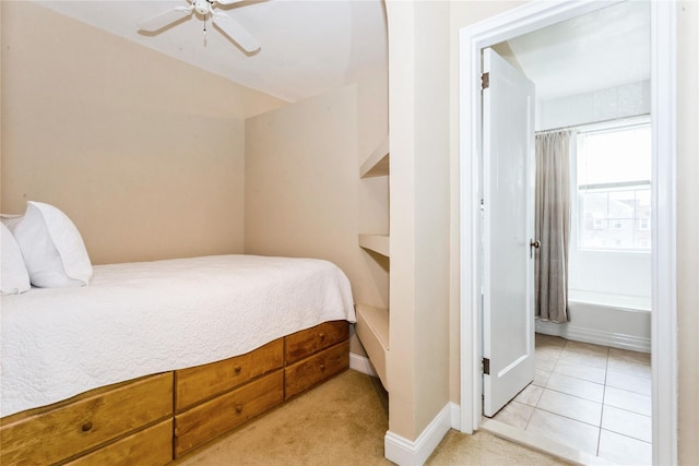 bedroom featuring light tile patterned flooring, light colored carpet, ceiling fan, and baseboards