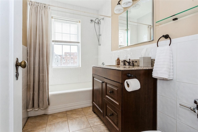 bathroom with tile patterned floors, shower / bath combo with shower curtain, tile walls, and vanity
