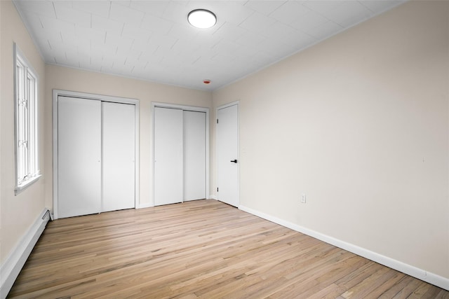 139 Cross Rd, Goshen, NY 10924 - unfurnished bedroom with a baseboard radiator, light wood finished floors, two closets, and baseboards
