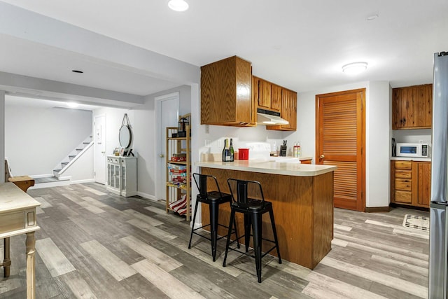 25 Macgregor Dr, Mahopac, NY 10541 - kitchen with under cabinet range hood, light wood-style floors, brown cabinets, and white microwave