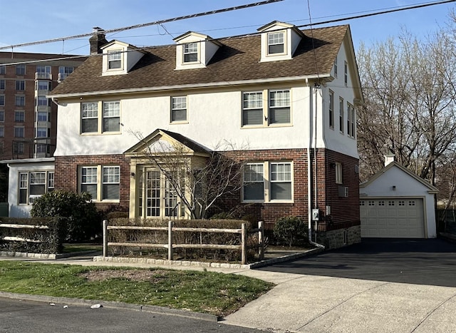 view of front of home with stucco siding, brick siding, fence, and an outdoor structure