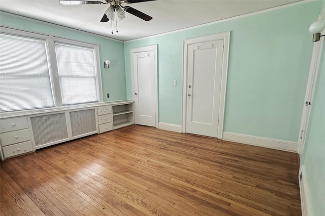 interior space with radiator heating unit, baseboards, light wood-style floors, and ceiling fan