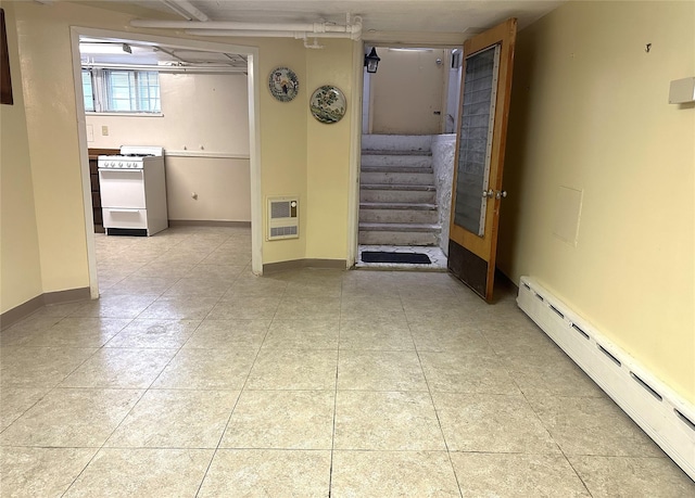 empty room with a baseboard radiator, heating unit, baseboards, and stairway