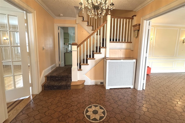 staircase featuring a notable chandelier, crown molding, and a textured ceiling