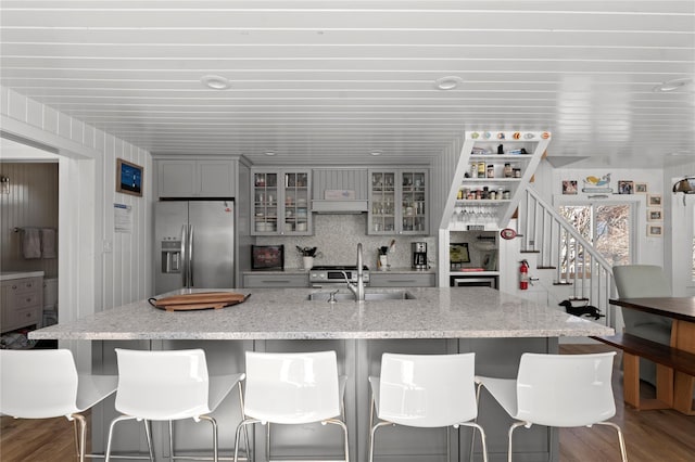 110 Ocean Rd, Ocean Beach, NY 11770 - kitchen with stainless steel fridge, gray cabinets, a sink, a kitchen breakfast bar, and glass insert cabinets