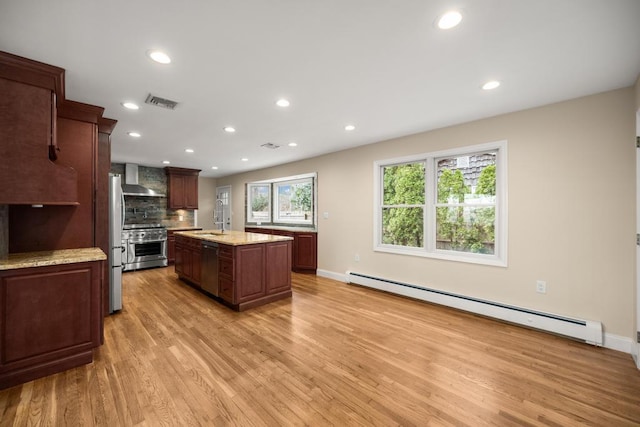 kitchen featuring appliances with stainless steel finishes, a sink, a baseboard heating unit, light wood-style floors, and wall chimney exhaust hood