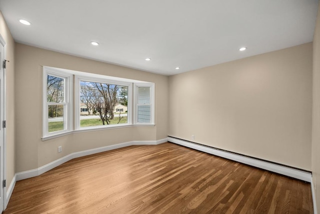 spare room featuring recessed lighting, baseboards, a baseboard heating unit, and wood finished floors
