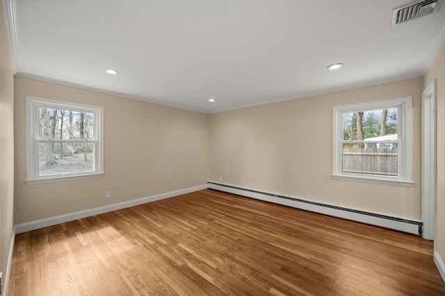 spare room with visible vents, crown molding, wood finished floors, baseboards, and a baseboard radiator