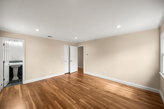 unfurnished bedroom featuring crown molding, baseboards, and wood finished floors