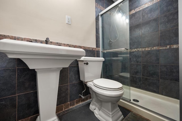 bathroom with wainscoting, a shower stall, toilet, and tile walls