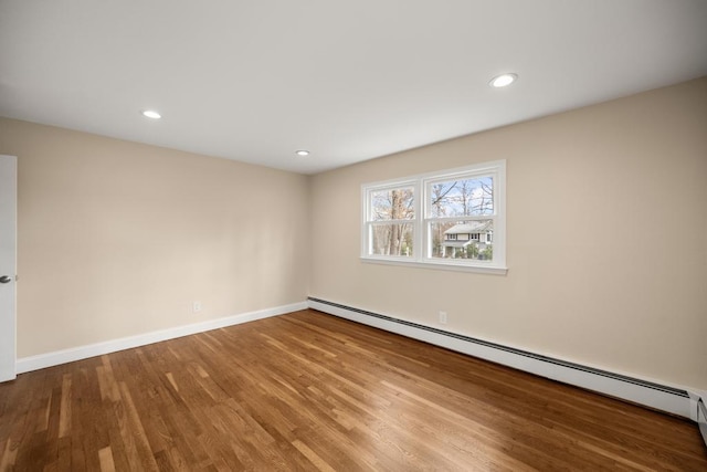 spare room featuring baseboards, a baseboard radiator, wood finished floors, and recessed lighting
