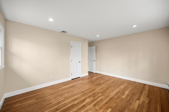 empty room featuring light wood-style floors, baseboards, recessed lighting, and visible vents