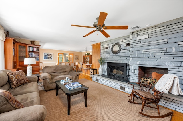 living room with a stone fireplace, a ceiling fan, a chandelier, and recessed lighting