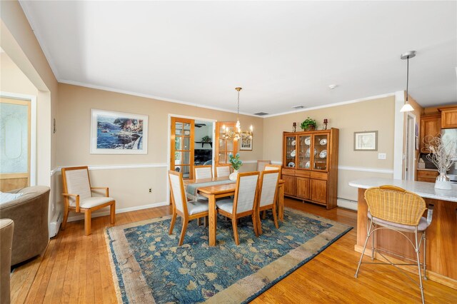 dining space with light wood-style floors, a chandelier, a baseboard radiator, baseboards, and ornamental molding