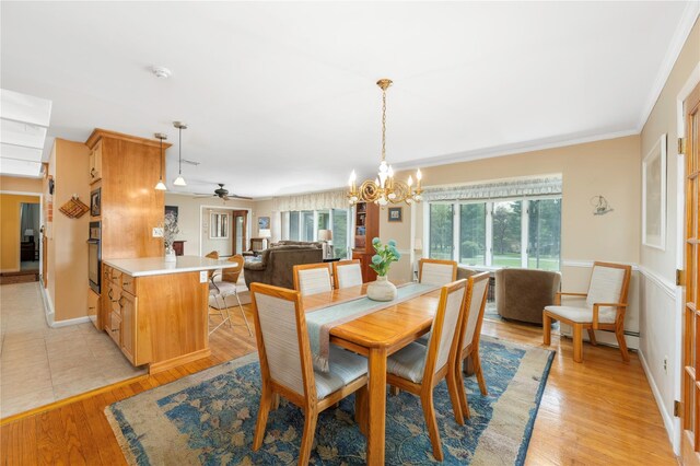 dining room featuring a chandelier, ceiling fan, light wood-style floors, a baseboard radiator, and crown molding