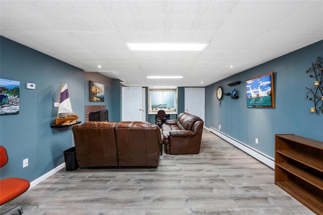 living room featuring a baseboard heating unit, wood finished floors, baseboards, and recessed lighting