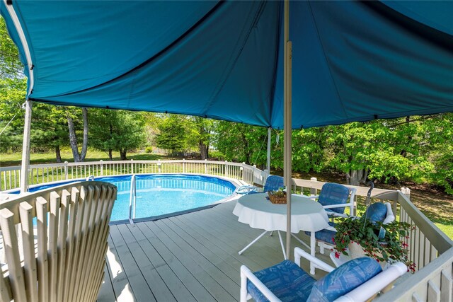 view of swimming pool with a deck and view of scattered trees